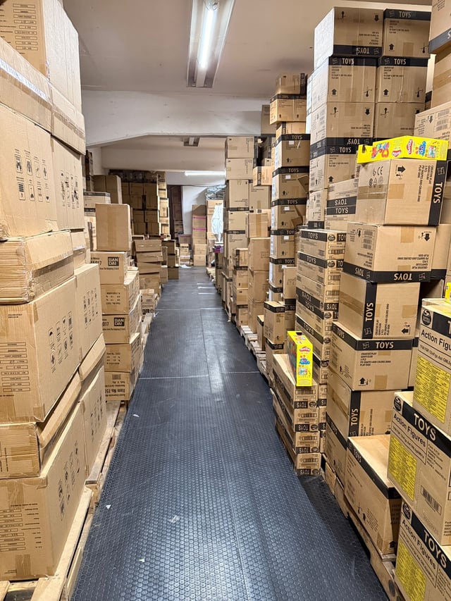 Pasillo estrecho flanqueado por cajas acomodadas sobre tarimas
