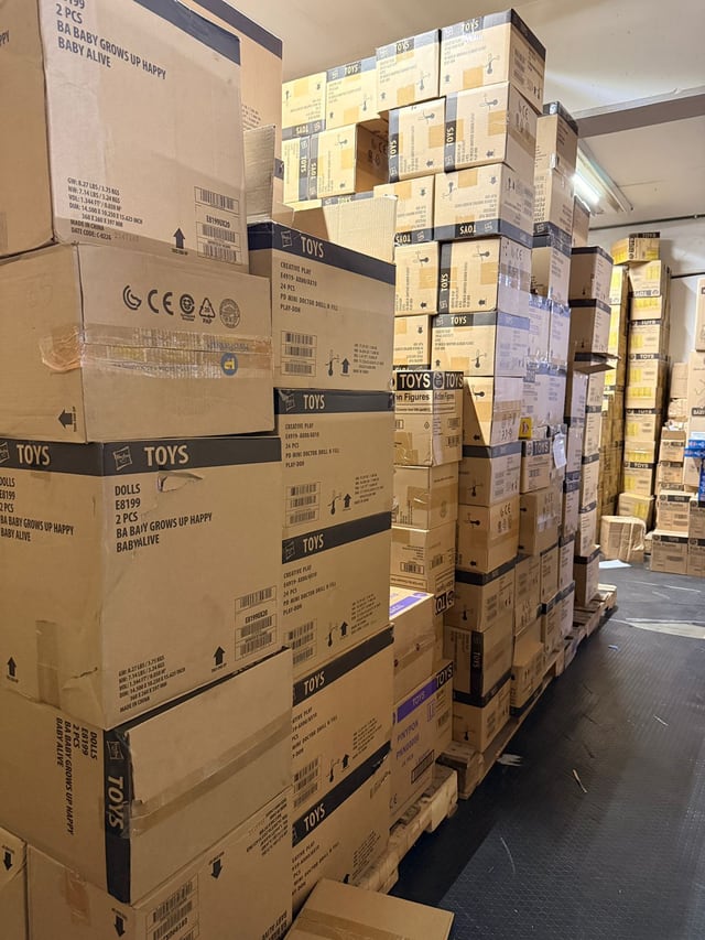 Fila de cajas apiladas sobre tarimas observada desde un extremo del pasillo