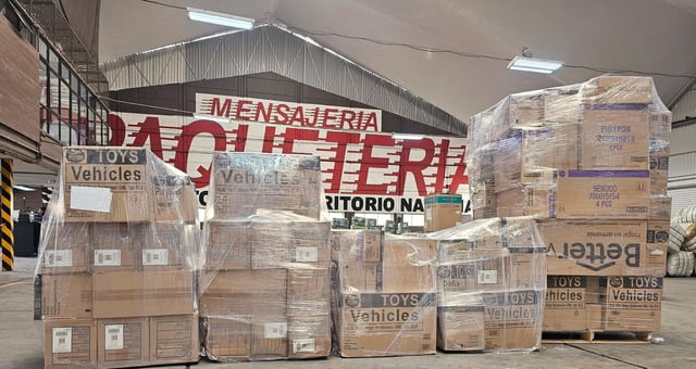 Conjuntos de cajas envueltos en película plástica frente a señalización mural