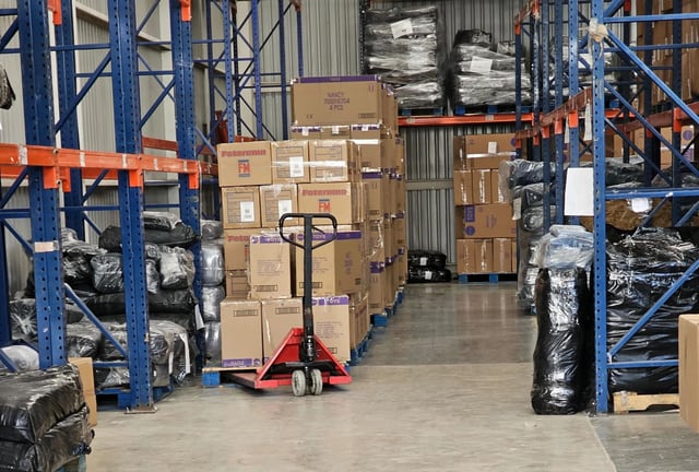 Pasillo de anaqueles altos con cajas y paquetes acomodados en distintos niveles